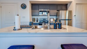A modern kitchen with a central island, stainless steel appliances, and a clock on the wall. - 1 BR 1 BA Luxury - Museum District & Downtown HTX (Houston)