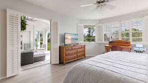 A bedroom with a large bed, a dresser, a desk, and a television.