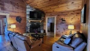 A log cabin interior with leather sofas, a stone fireplace, and a mounted television. - Lake View Cabin in ranger GA 4 Bedrooms (Ranger)
