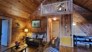 A wooden interior with a sofa, a table with a vase, a lamp, and a painting on the wall. - Lake View Cabin in ranger GA 4 Bedrooms (Ranger)