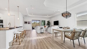A modern kitchen with a central island, bar stools, and a dining area with wicker chairs. - New Listing! Charlotte Harbor Area Resort, 120mi to Disney & 134mi to Universal - GRH575527 (Punta Gorda)