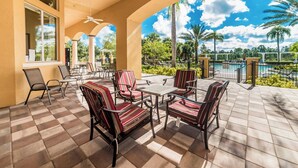 A covered patio with outdoor furniture, a pool, and a view of palm trees and a clear sky. - New Listing! Watersong Resort, 9mi to Disney & 18mi to Universal - FS384051 (Davenport)