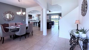 A spacious dining area with a high ceiling and modern decor, leading to a kitchen and a living area with a view of the outdoors. - New Listing! Watersong Resort, 9mi to Disney & 18mi to Universal - FS384051 (Davenport)