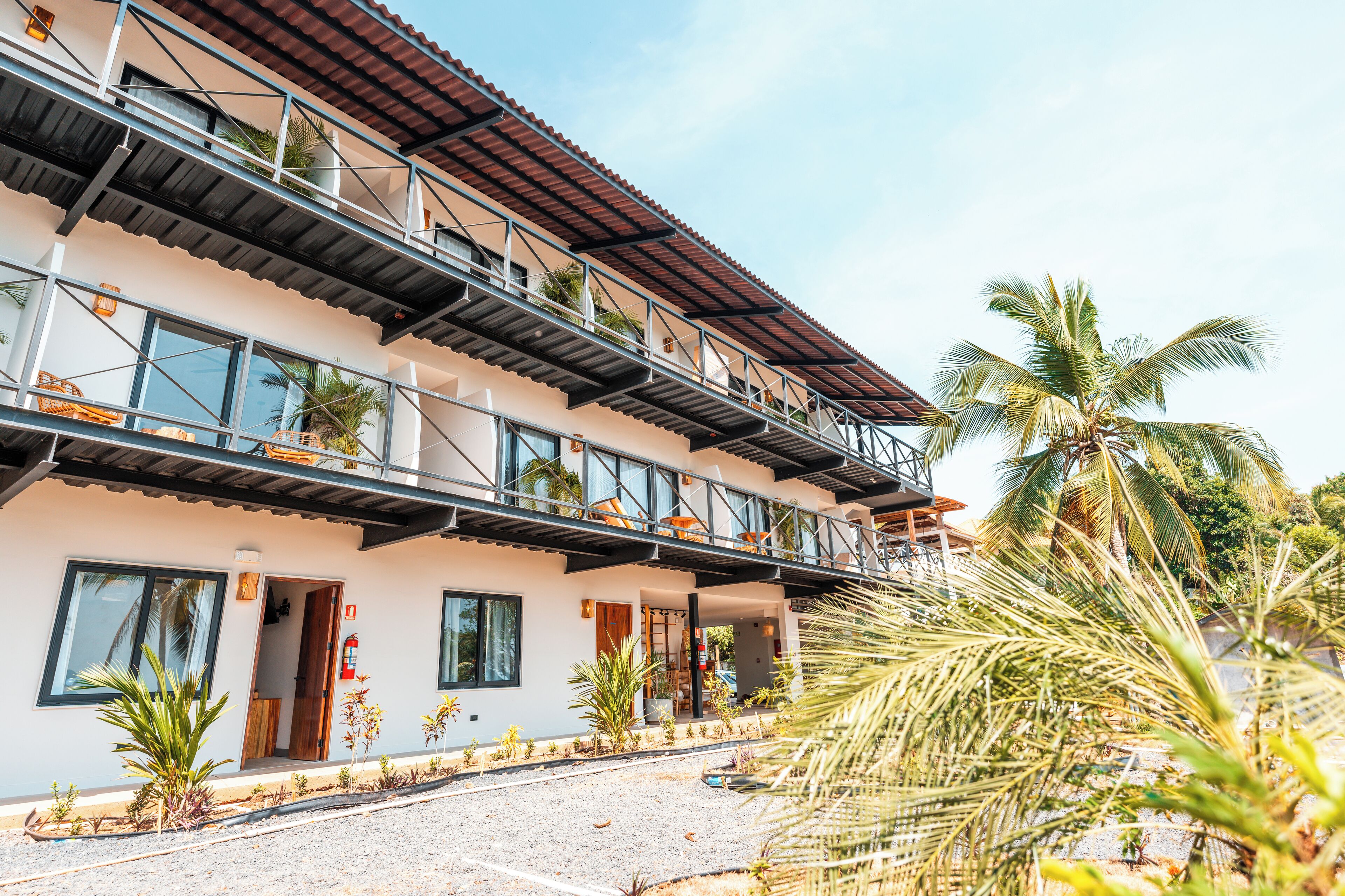 A multi-story hotel with balconies, large windows, and a paved driveway.