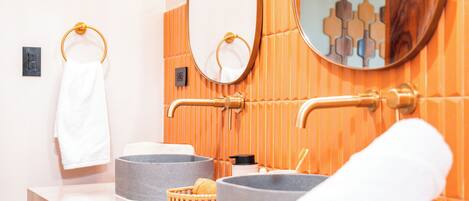 A bathroom with a white countertop, two grey bowls, a wooden basket, and a white towel.