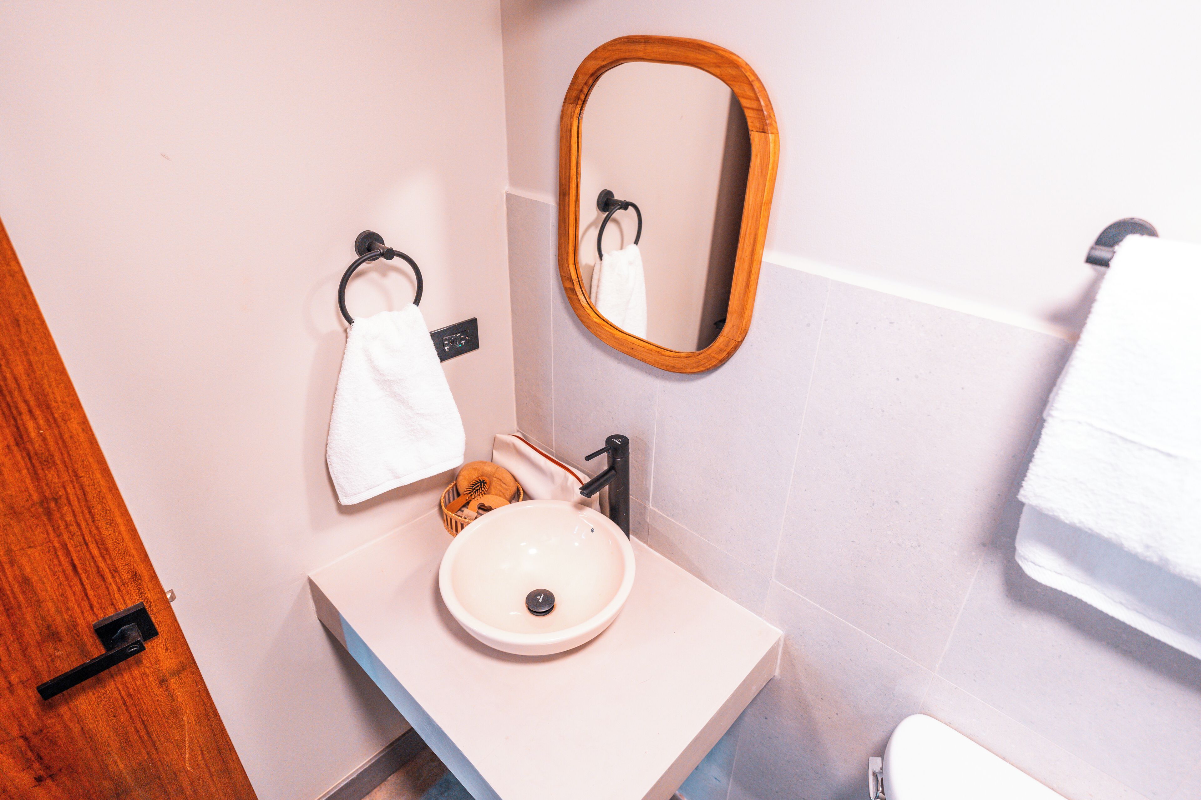 A bathroom with a white sink, a wooden-framed mirror, and a towel rack.