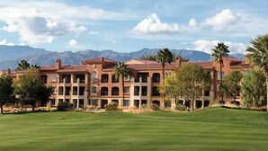 A multi-story hotel with a red-tiled roof, surrounded by a well-maintained lawn and palm trees, with mountains in the background. - Marriott's Shadow Ridge 1- The Villages 1 Bedroom- perfect for Coachella. (Palm Desert)