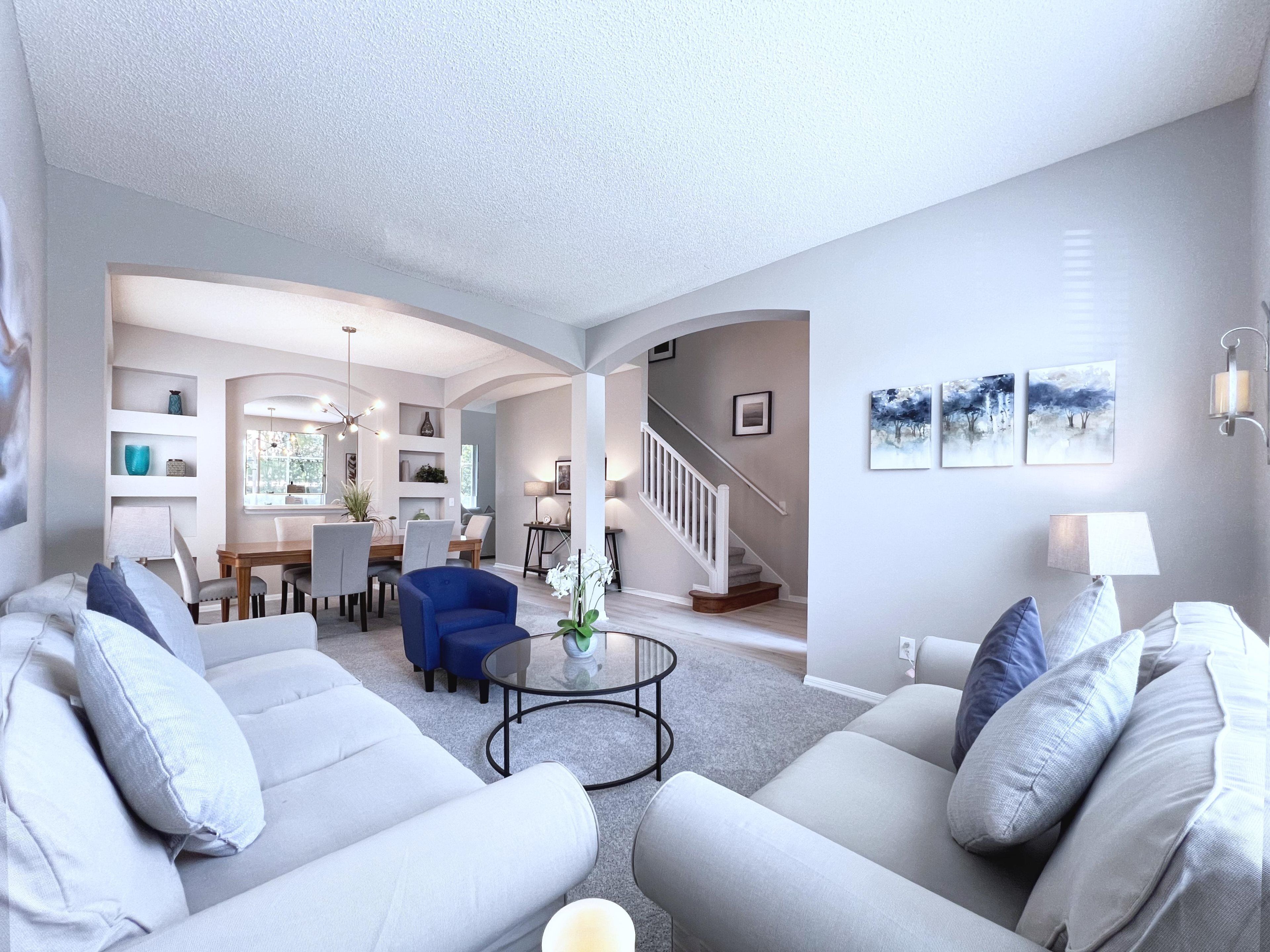 A modern living room with a sofa set, a coffee table, and a dining area with chairs and a table.