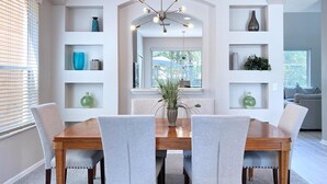 A dining room with a wooden table and grey upholstered chairs, surrounded by white shelving units with decorative items. - New Listing! Terra Verde Resort, 6mi to Disney & 12mi to Universal - FS59000 (Kissimmee)
