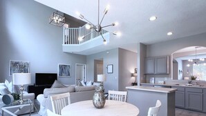A modern kitchen with a central island, a dining area with a round table, and a living room with a sofa and a TV. - New Listing! Terra Verde Resort, 6mi to Disney & 12mi to Universal - FS59000 (Kissimmee)