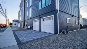 A two-story building with a dark exterior and white trim around windows and garage doors. - Spacious 4BR with rooftop deck – ocean views & beach access (Seaside Heights)