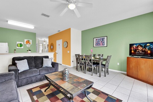 A living room with a sofa, coffee table, and dining area with chairs and a table.