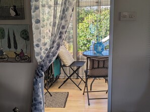 A room with a view of greenery outside, a table with chairs, a blue lamp, and a patterned rug.