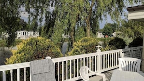 A deck with white railings, a table, and two chairs. - Beautiful 2 Bed Caravan Southview Park Skegness (Skegness)