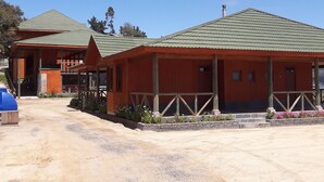 A two-story building with a green roof and a porch. There is a dirt path leading to the entrance. - Habitamar Lago Vichuquen (Vichuquen)