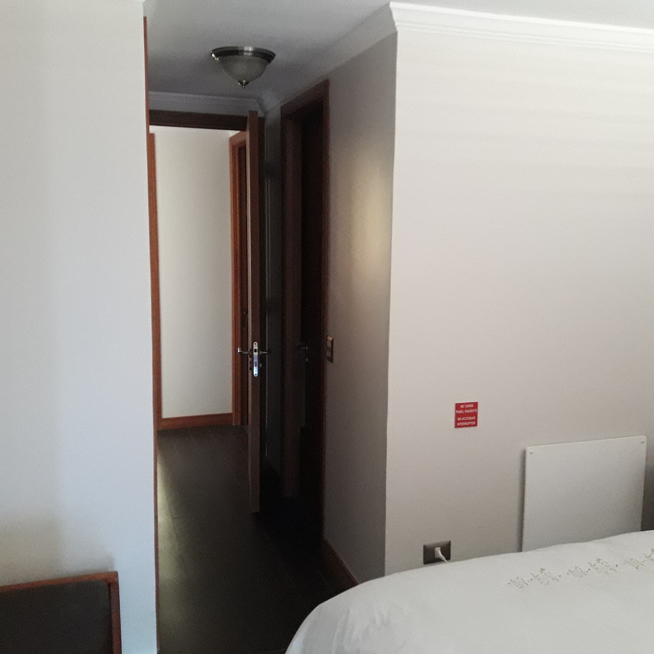 A hotel room with a bed, a door, and a hallway.