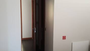 A hotel room with a bed, a door, and a hallway.