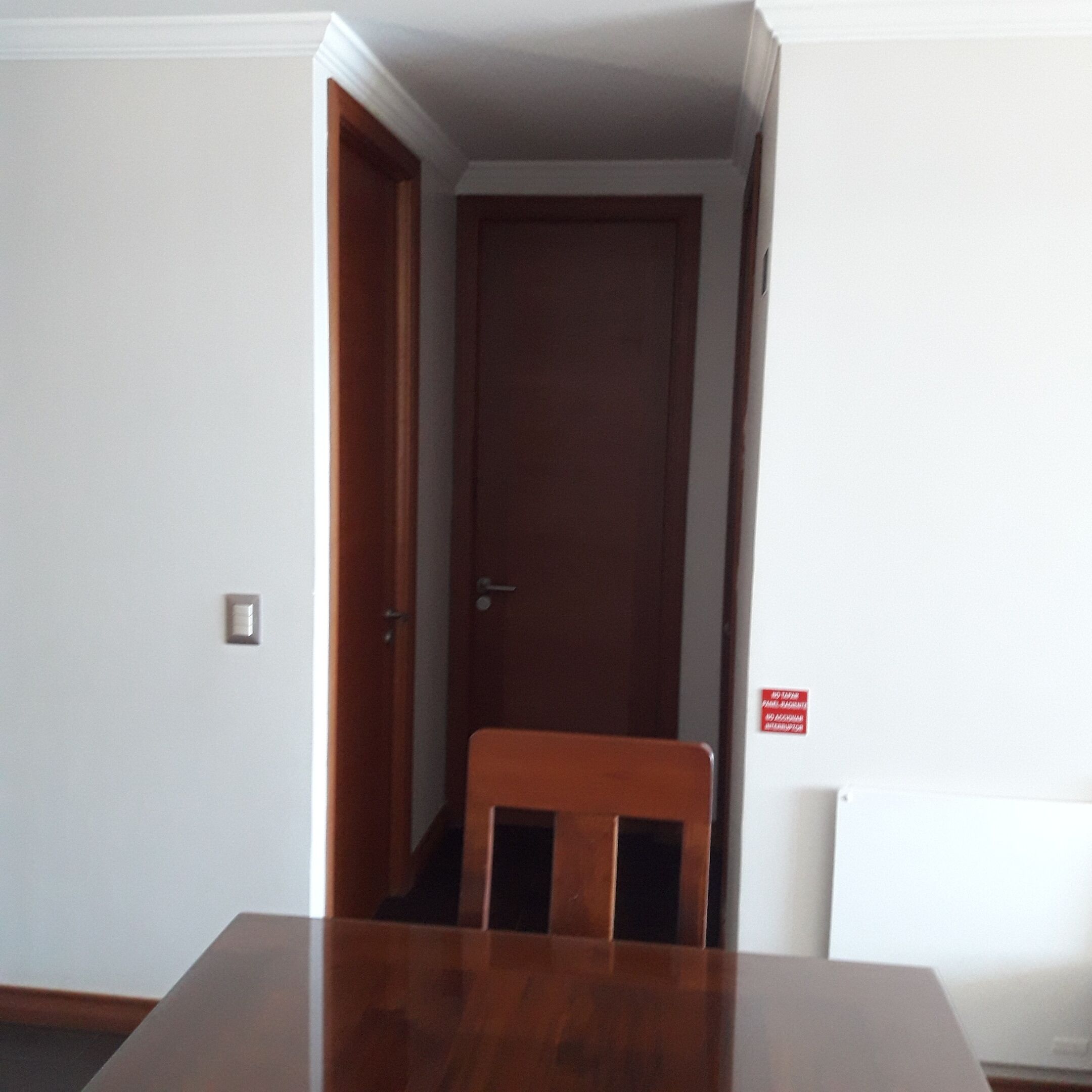 Una habitación con una mesa de madera, una silla y una puerta cerrada.
