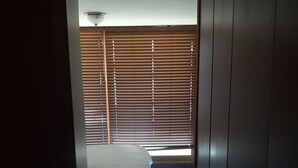 A bedroom with a bed, a wardrobe, and a window with blinds. - Habitamar Lago Vichuquen (Vichuquen)