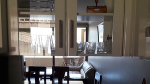 A dining area with a table and chairs, a sofa, and a view of a balcony with a railing. - Habitamar Lago Vichuquen (Vichuquen)