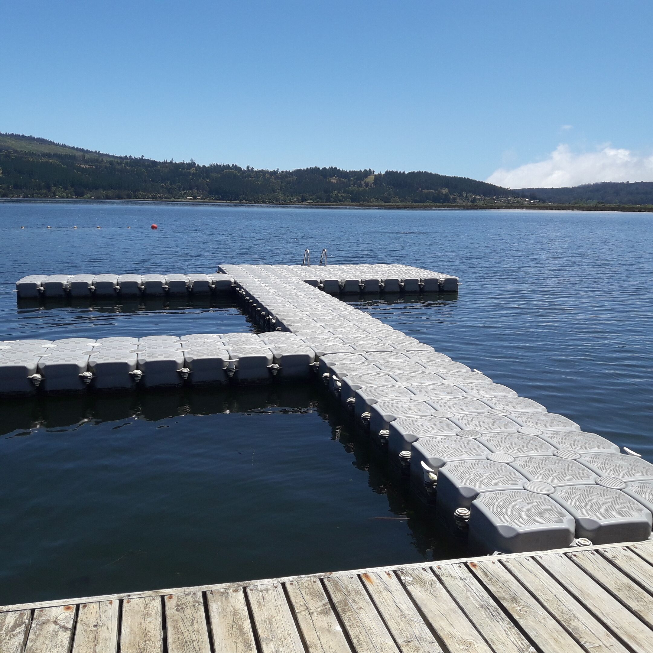 A wooden dock extending into a lake with a clear sky.