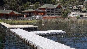 A waterfront hotel with a dock extending into the water, surrounded by trees and other buildings. - Habitamar Lago Vichuquen (Vichuquen)