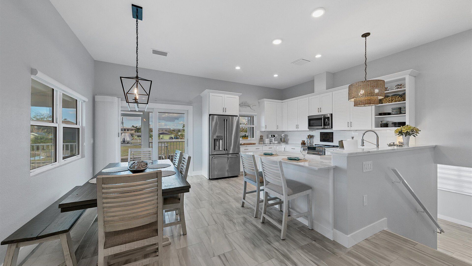 A modern kitchen with white cabinetry, stainless steel appliances, and a dining area with a wooden table and chairs.