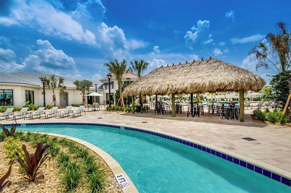 A swimming pool with a 3 FT depth marker, surrounded by lounge chairs and a thatched umbrella.