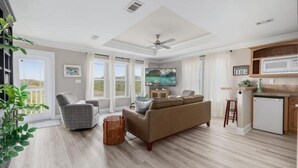 Amplia sala de estar con sofá, sillón y televisión. Zona de cocina con microondas y refrigerador.