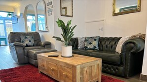 A living room with a leather sofa, a wooden coffee table, a red shag rug, and a potted plant. - House few Mins From Beach With hot tub & Sauna (Shoreham-by-Sea)