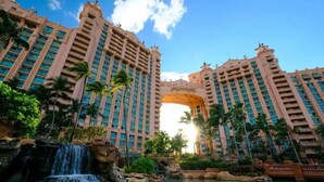 A large hotel with multiple high-rise buildings, a central archway, and a waterfall in the foreground. - COMPLIMENTARY CAR! CASA DEL MAR! (Nassau)