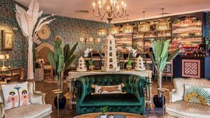 A luxurious interior with a plush green sofa, ornate chandeliers, and a variety of decorative items and furniture. - COMPLIMENTARY CAR! CASA DEL MAR! (Nassau)