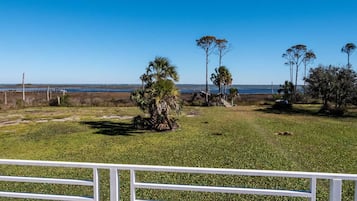 Enjoy a serene ocean view from this tranquil outdoor space surrounded by lush trees and a grassy field.