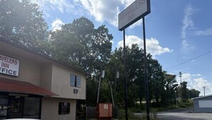 Un bâtiment avec une enseigne indiquant « Travelers Inn », un parking et une voiture.