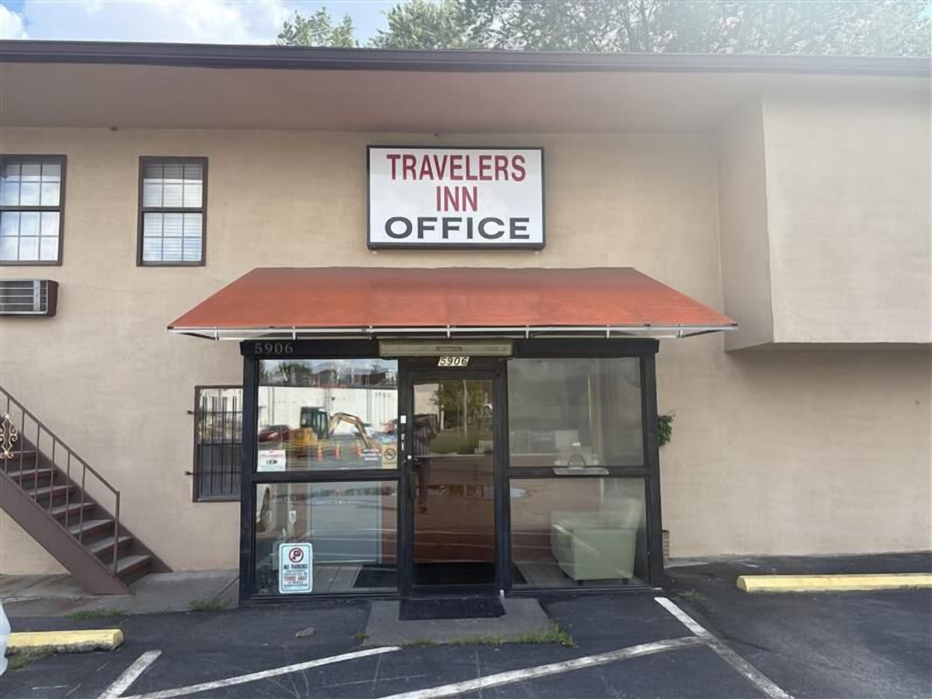 Un edificio con un letrero que dice 'TRAVELERS INN OFFICE' y un acceso cubierto.