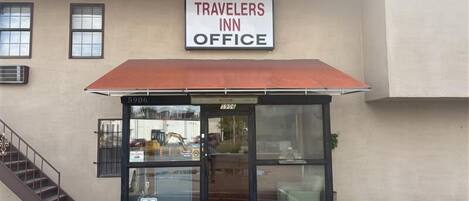 A building with a sign reading 'TRAVELERS INN OFFICE' and a covered entrance.