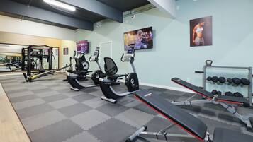 A gym with cardio machines, weightlifting equipment, and a mirror.