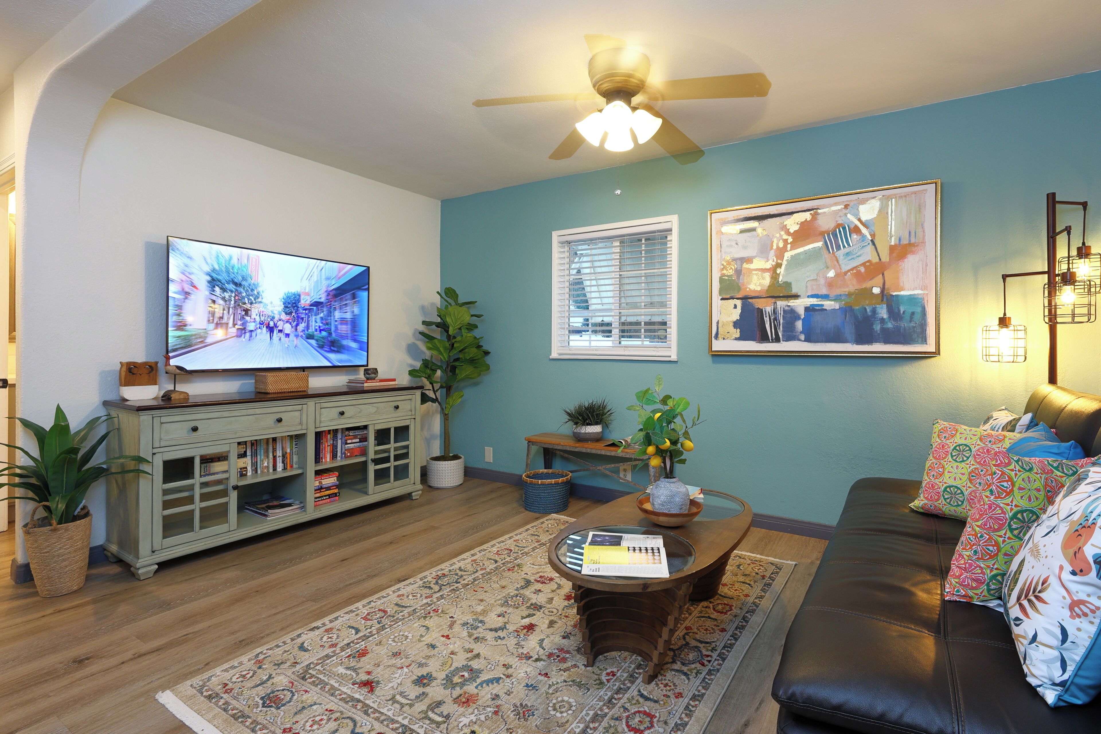 A living room with a television, sofa, coffee table, and decorative items.