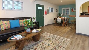 A living room with a sofa, coffee table, and a dining area with a table and chairs. - Stylish 2B2B Hideaway 10 mins. drive to Disneyland (Santa Ana)