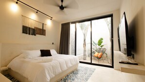 Ein modernes Schlafzimmer mit einem großen Bett, einem Deckenventilator, einem Fernseher und Blick ins Freie.