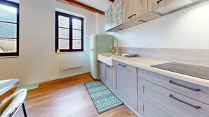A kitchen with a window, a refrigerator, and wooden cabinets. - La Renaissance Moderne (Kaysersberg)