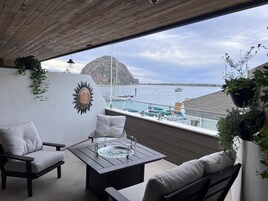 Un balcón con vistas al mar, que incluye una mesa, sillas y plantas en macetas.