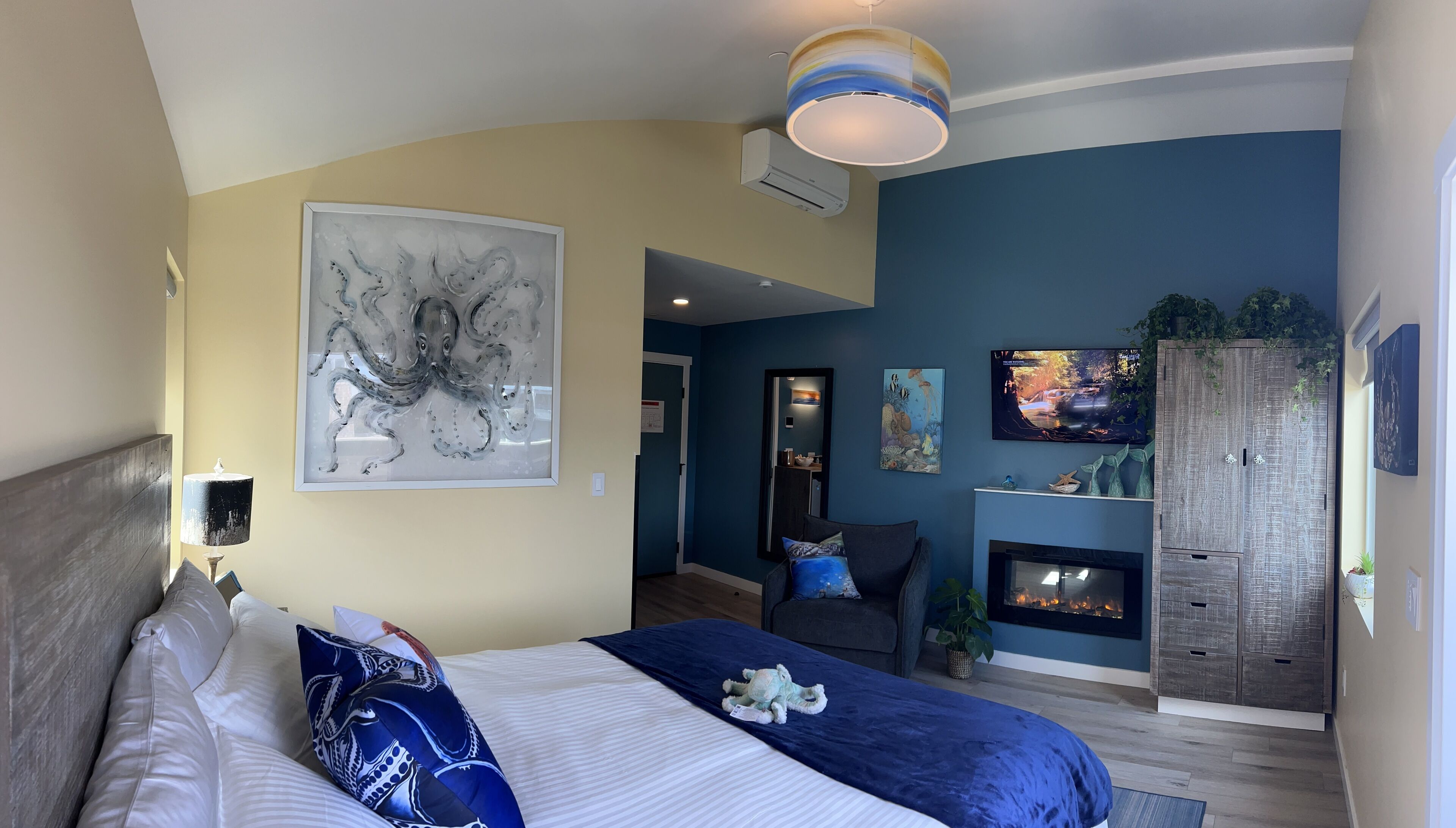 A modern bedroom with a large bed, a fireplace, and a wall-mounted TV.