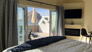 A bedroom with a bed, a TV, a desk, and a chair. - HarborWalk Inn (Morro Bay)
