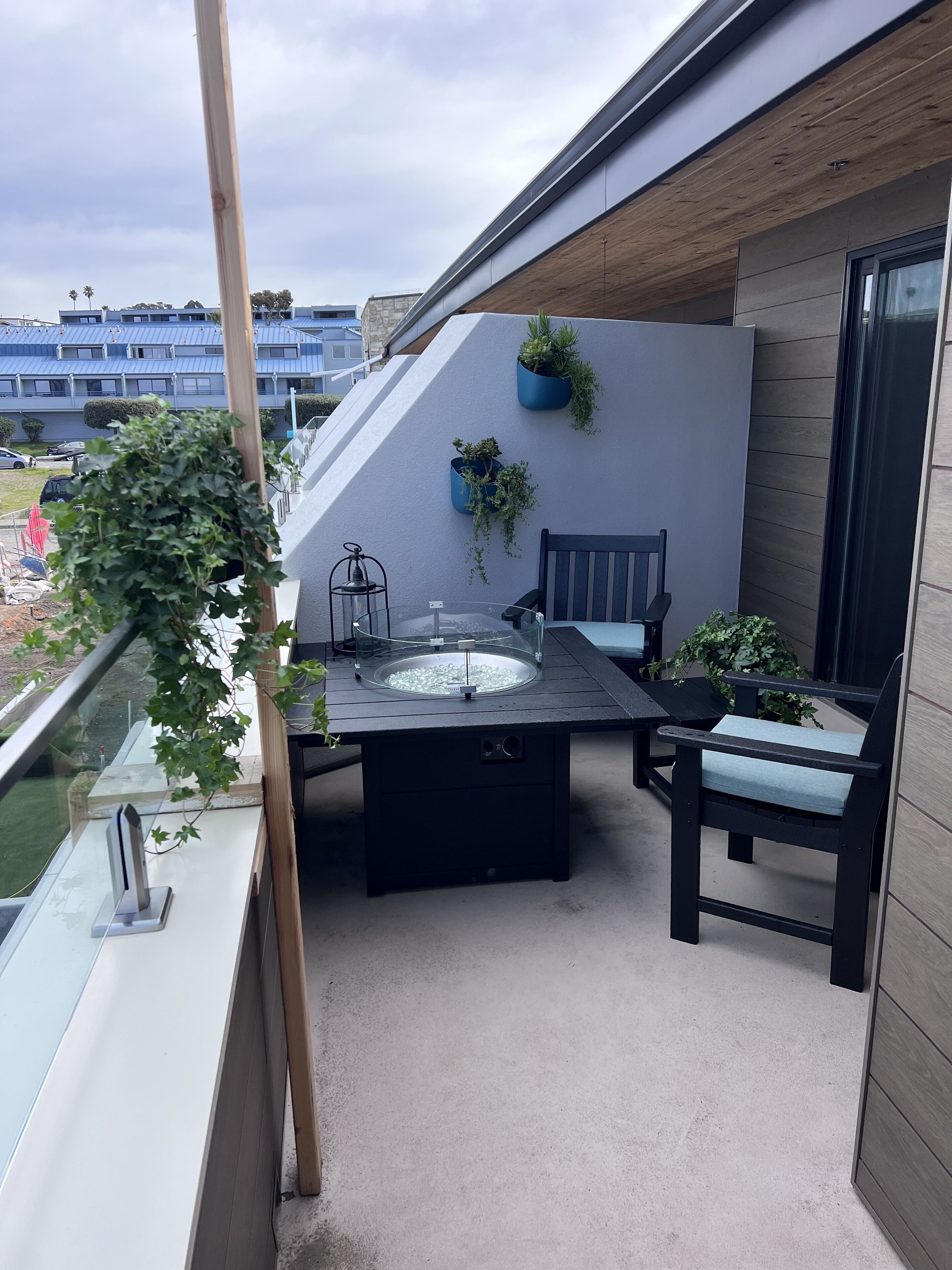 A balcony with a table and chairs, a small sink, and potted plants.