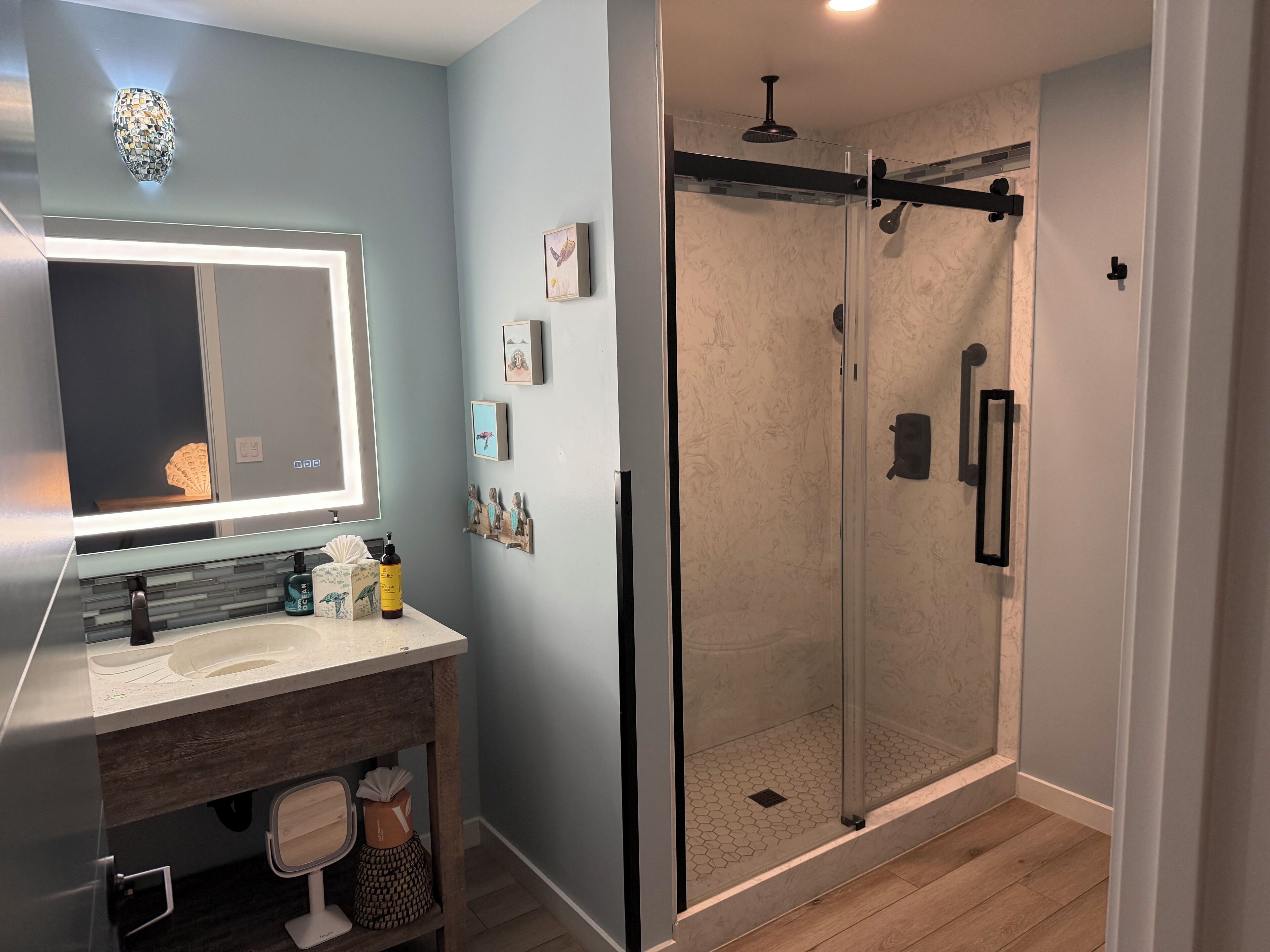 A modern bathroom with a glass-enclosed shower, a vanity with a mirror, and a sink.
