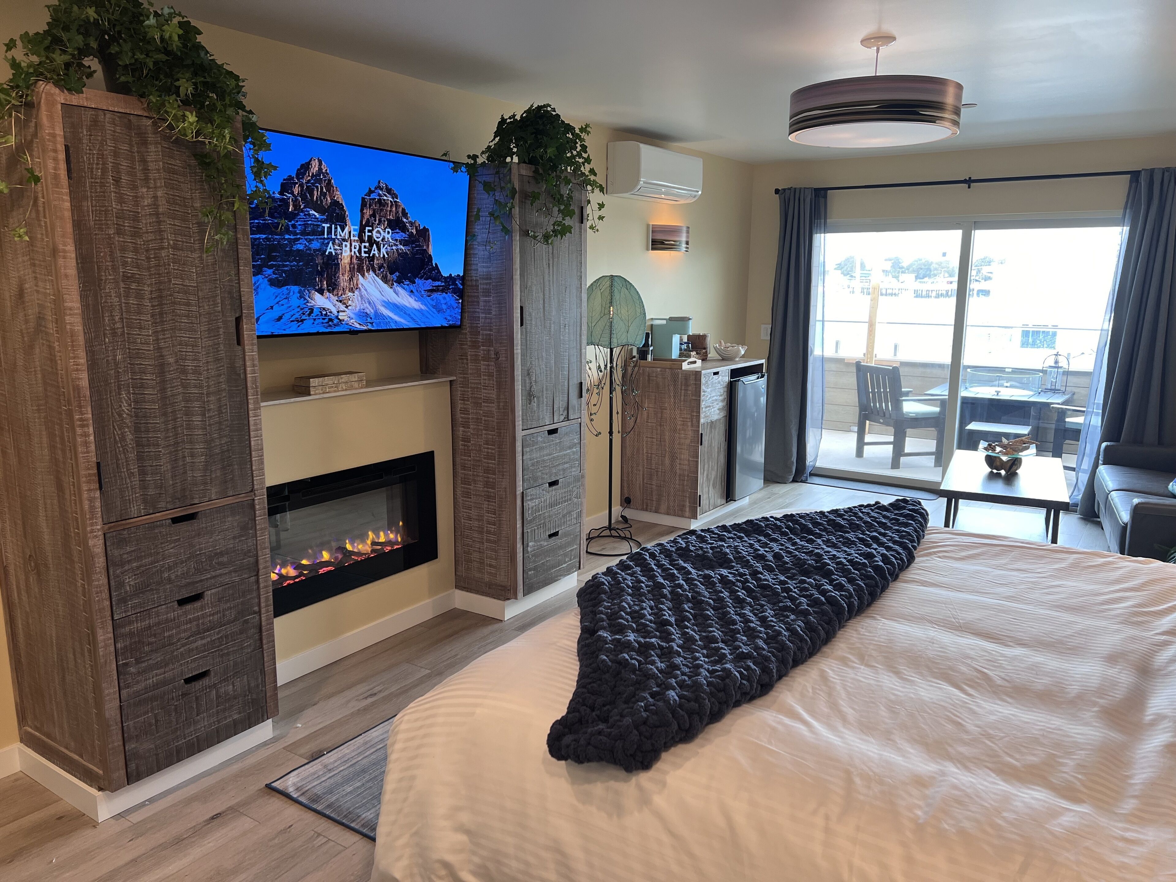Ett modernt hotellrum med en öppen spis, en stor säng, en tv och en balkong med utsikt.
