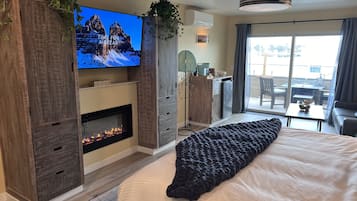 Ett modernt hotellrum med en öppen spis, en stor säng, en tv och en balkong med utsikt.