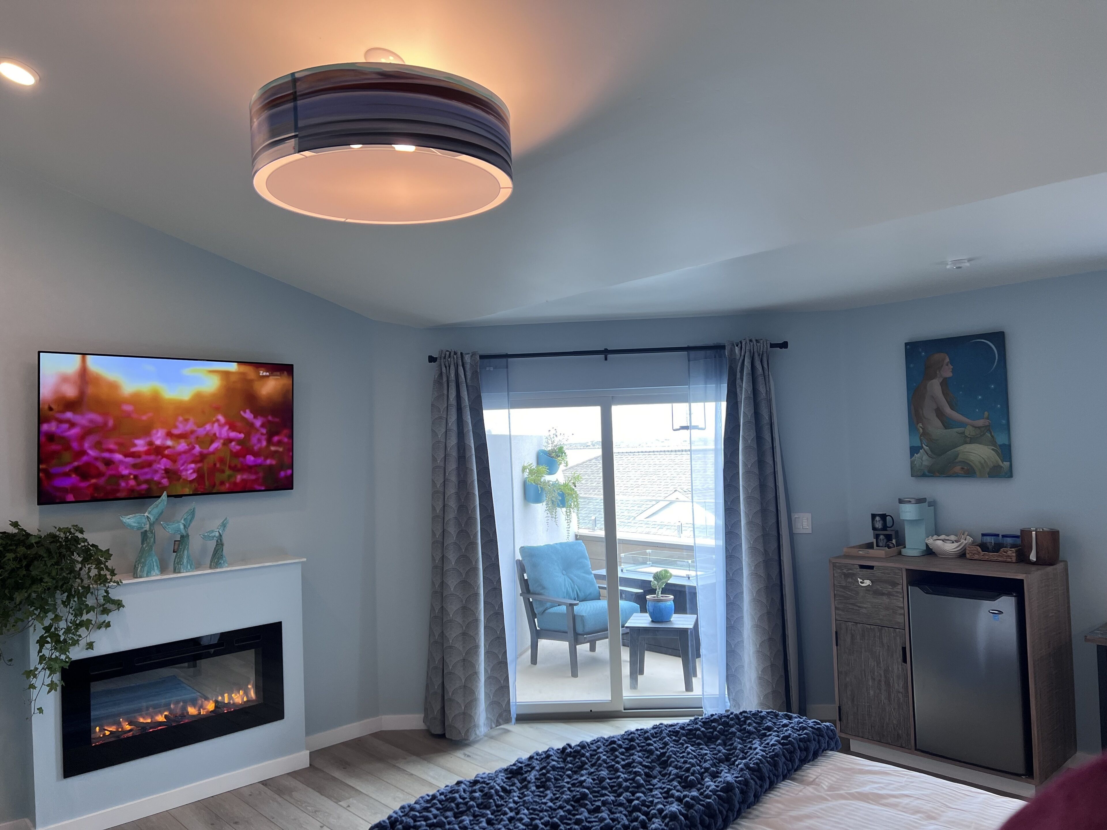 Ein modernes Wohnzimmer mit Kamin, Fernseher, einem Gemälde und Blick ins Freie.
