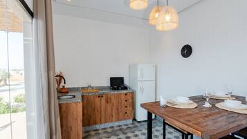 Ett kompakt kök med träskåp, ett vitt kylskåp och ett matbord med plats för två personer.